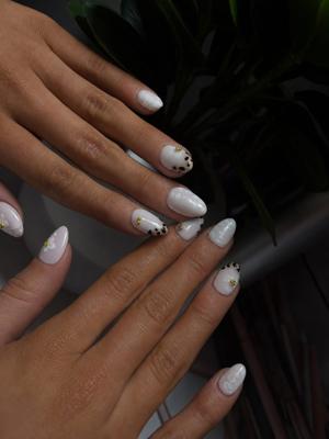 Almond nails in pearly white with black dot detailing and gold studs