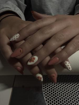 Pink almond nails with white polka dots and floral accent nails