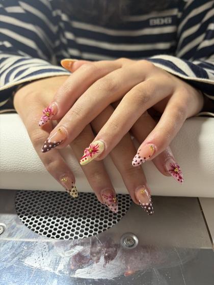 Long stiletto nails with dotted brown french tips, pink painted lilies, and gold gems