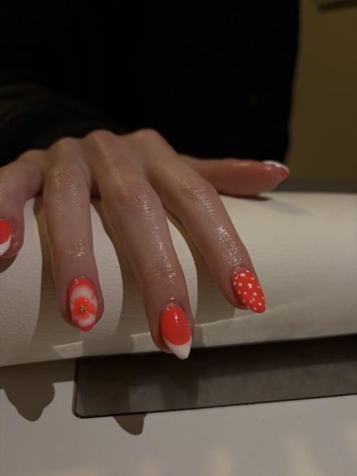 Coral nails with white french tips, polka dots, and a 3D white flower accent