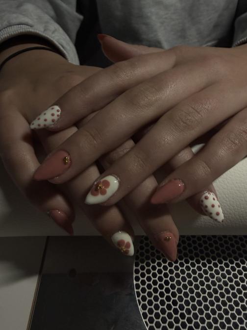 Pink almond nails with white polka dots and floral accent nails