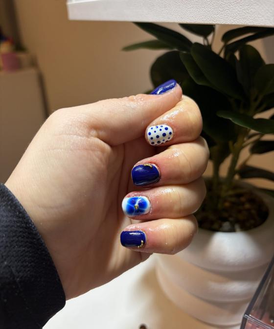 Short cobalt blue nails with white polka dot and swirl accent nails