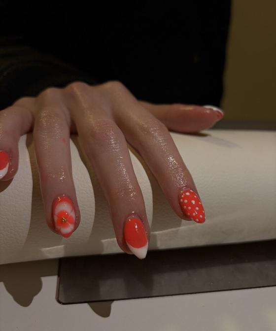 Coral nails with white french tips, polka dots, and a 3D white flower accent