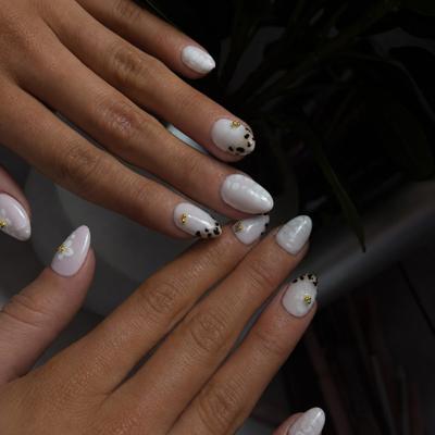 Almond nails in pearly white with black dot detailing and gold studs