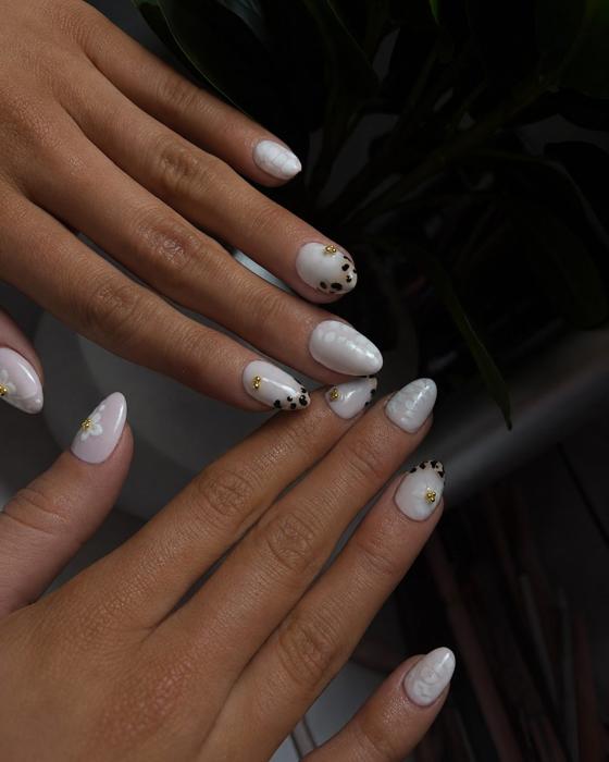 Almond nails in pearly white with black dot detailing and gold studs