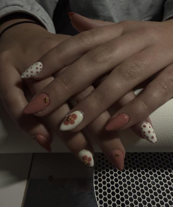 Pink almond nails with white polka dots and floral accent nails